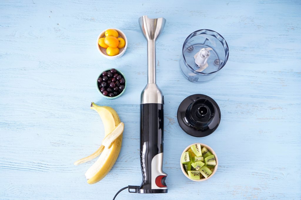 blender leżący na stole i owoce w miseczkach