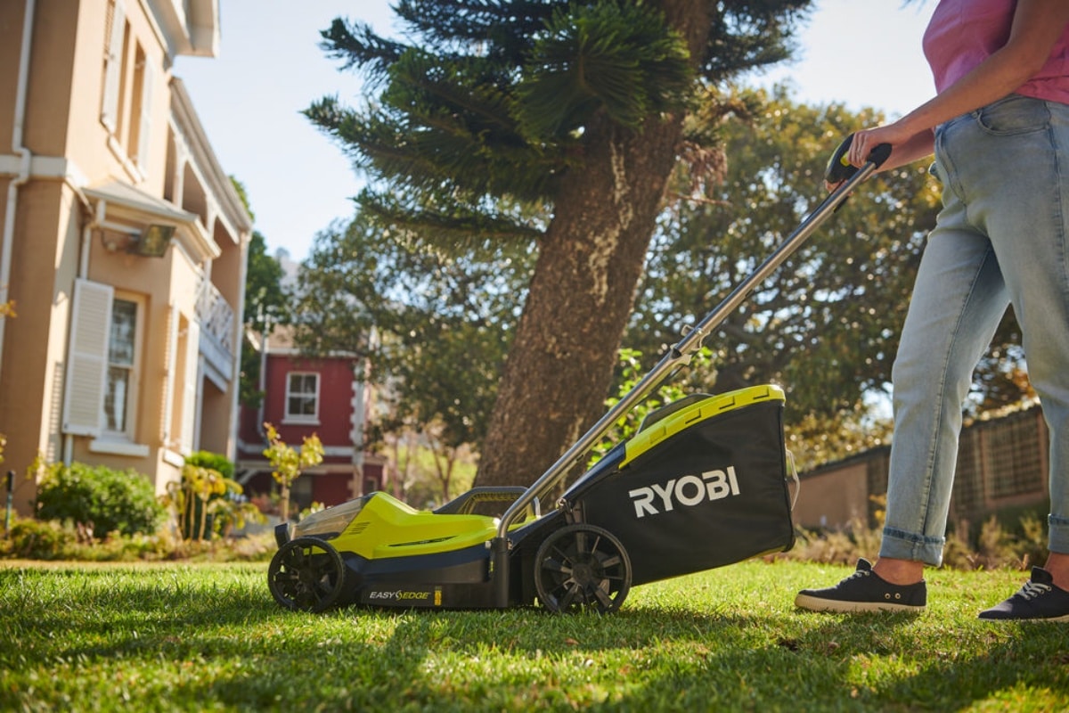 Kobieta kosi przydomowy trawnik kosiarką RYOBI