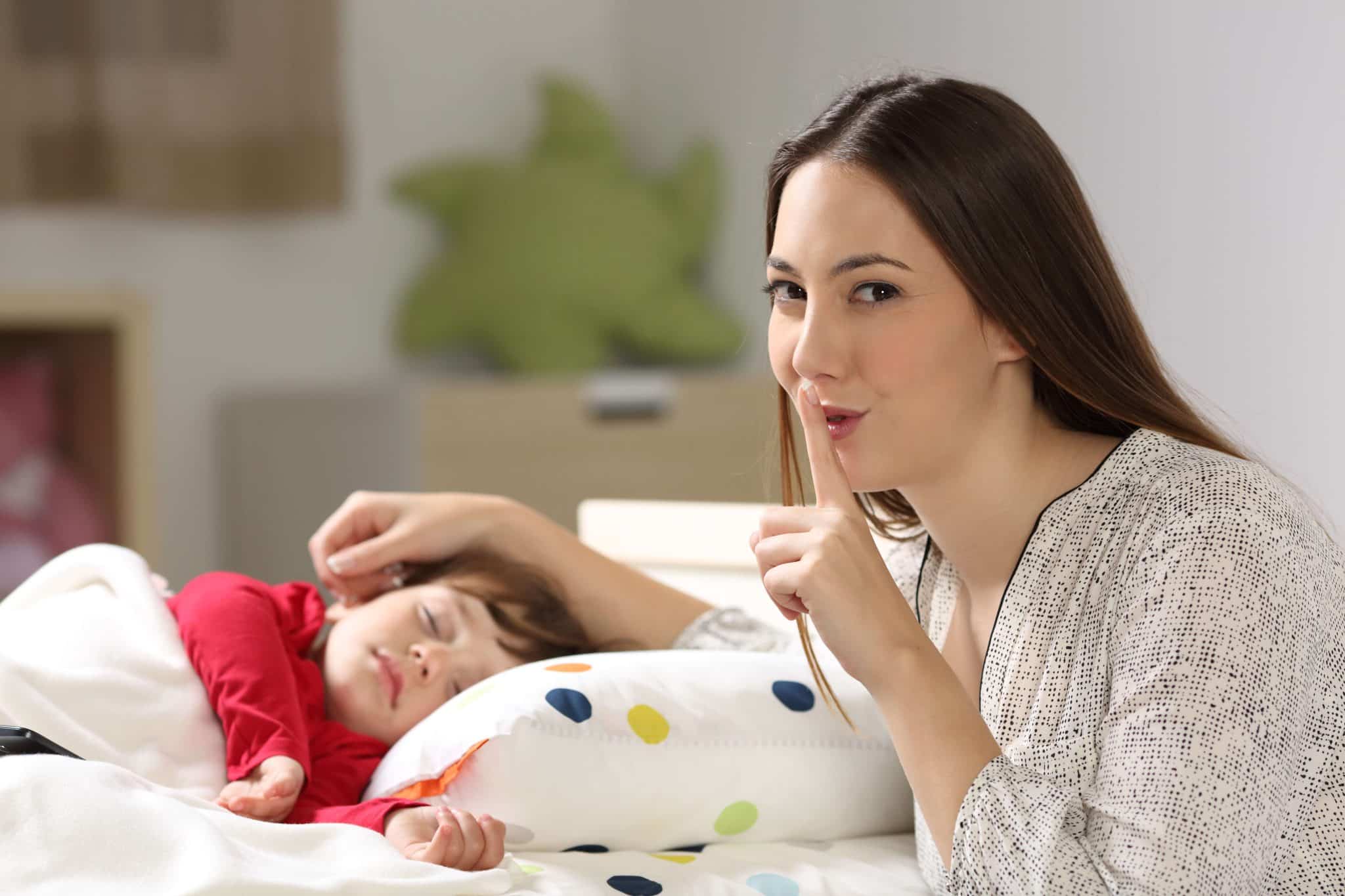 Mama gestem prosi o ciszę nad śpiącym dzieckiem