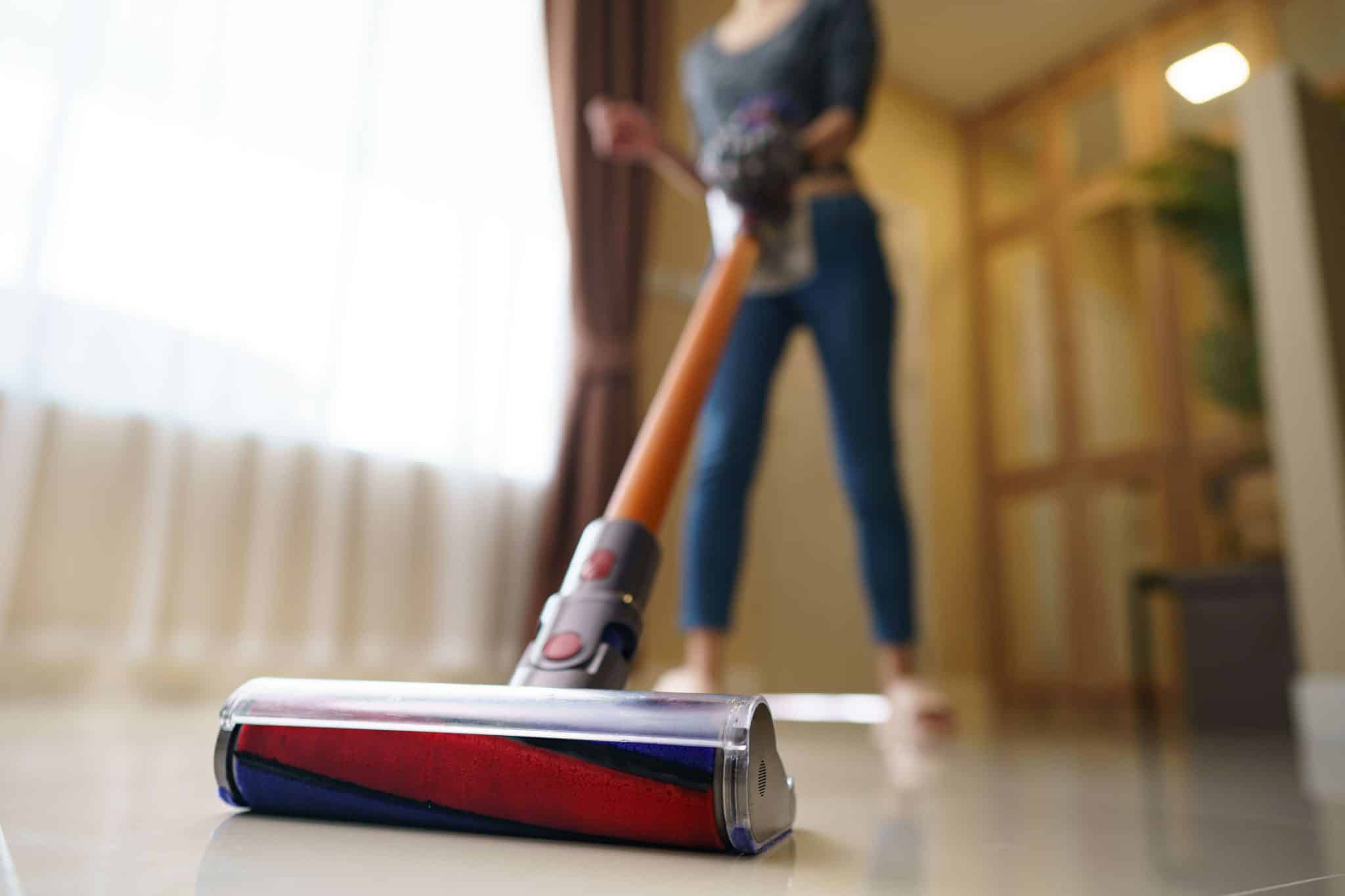 Kobieta odkurza podłogę modelem pionowym