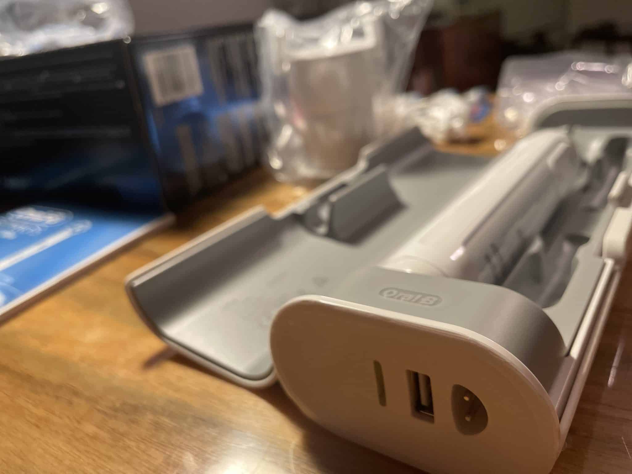 Etui Oral-B z funkcją ładowania i widocznymi wejściami: na ładowarkę i kable USB