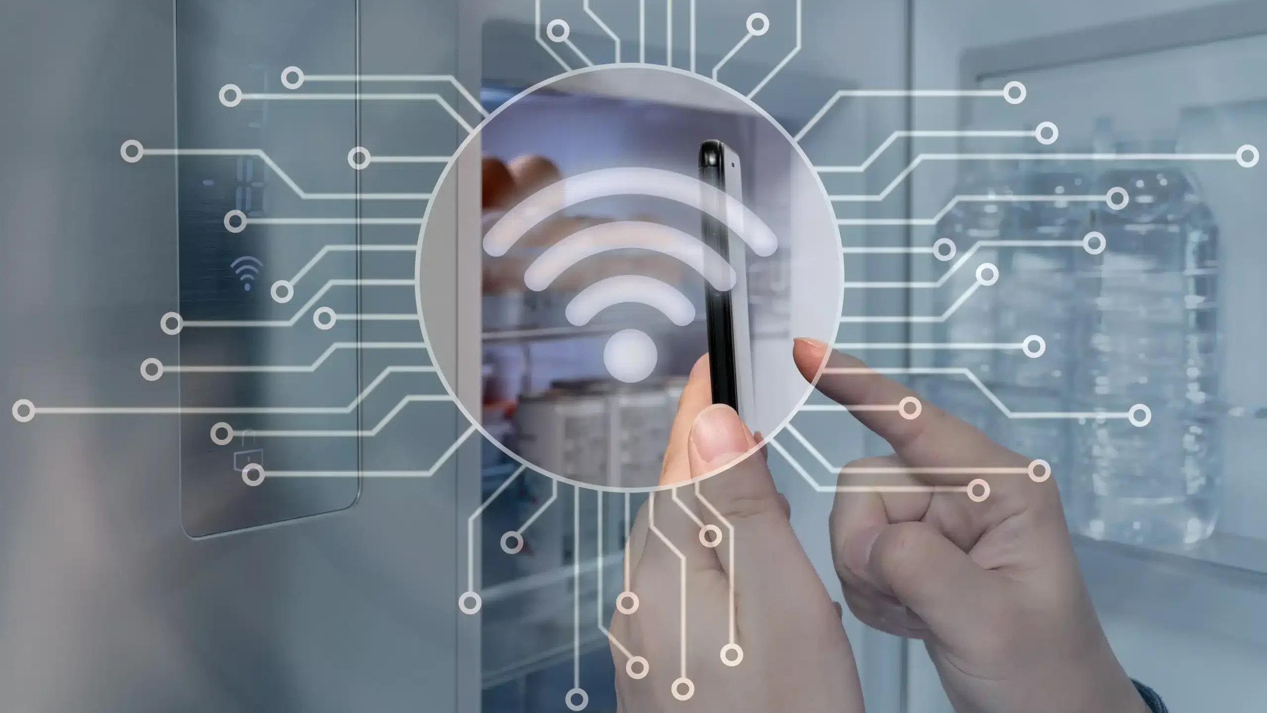 Dłonie trzymające smartfon z aplikacją mobilną do sterowania lodówką; w tle nowoczesna lodówka z modułem Wi-Fi i Bluetooth