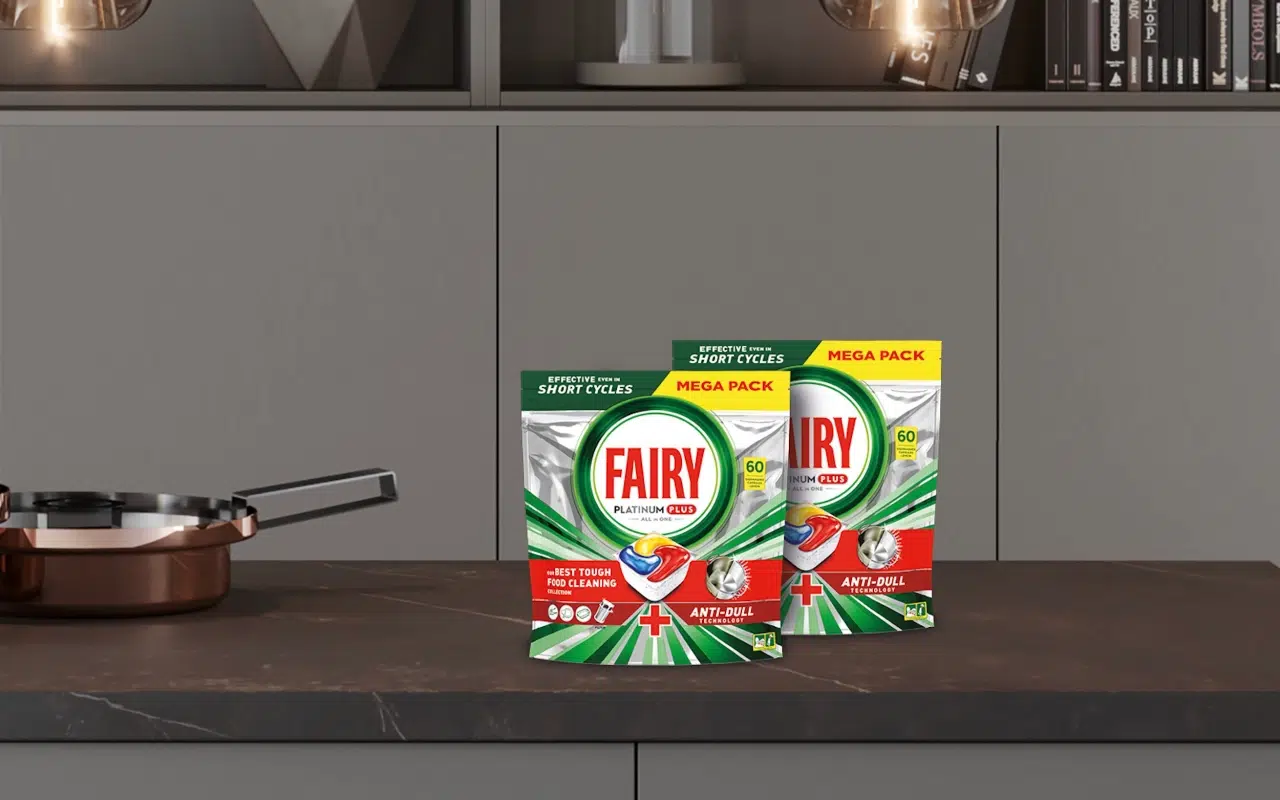 kapsułki Fairy Platinium Plus stoją na kuchennym blacie obok czystego naczynia