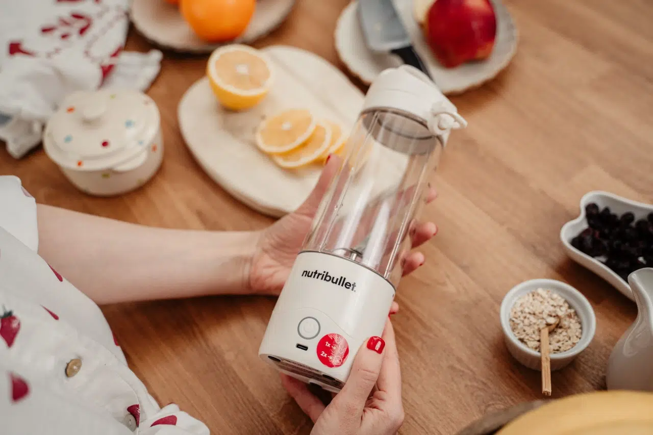 Kobieta trzyma w dłoniach bezprzewodowy blender nutribullet® Portable