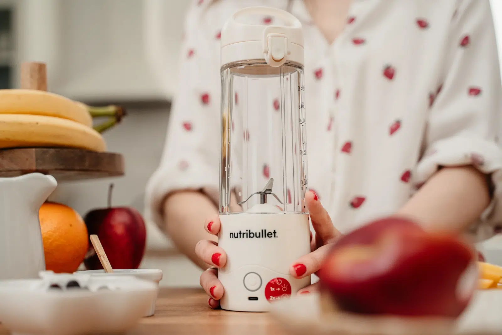 Przenośny blender do smoothie nutribullet® Portable ustawiony na blacie w towarzystwie owoców