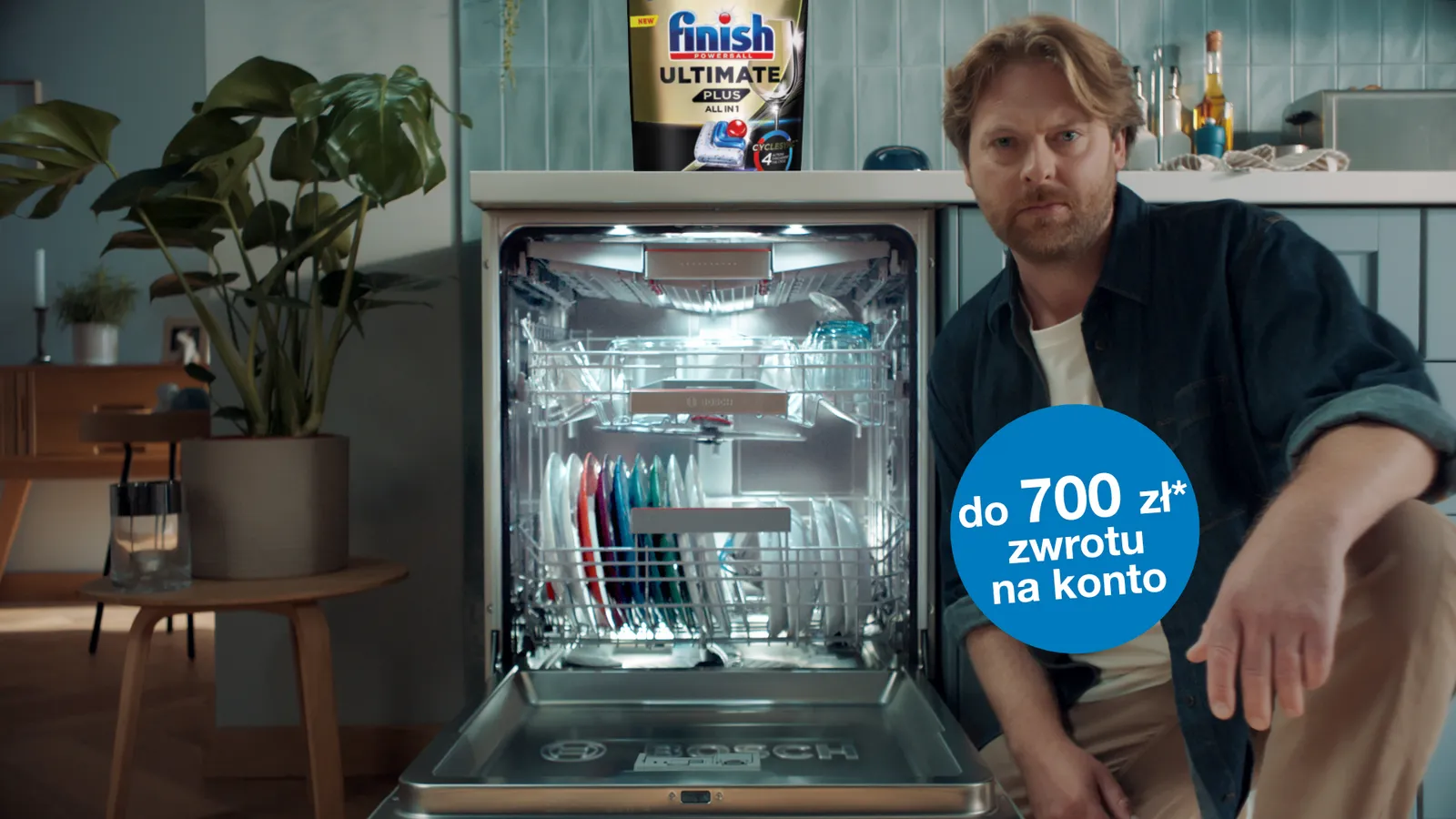 mężczyzna kuca obok otwartej, zapełnionej zmywarki Bosch